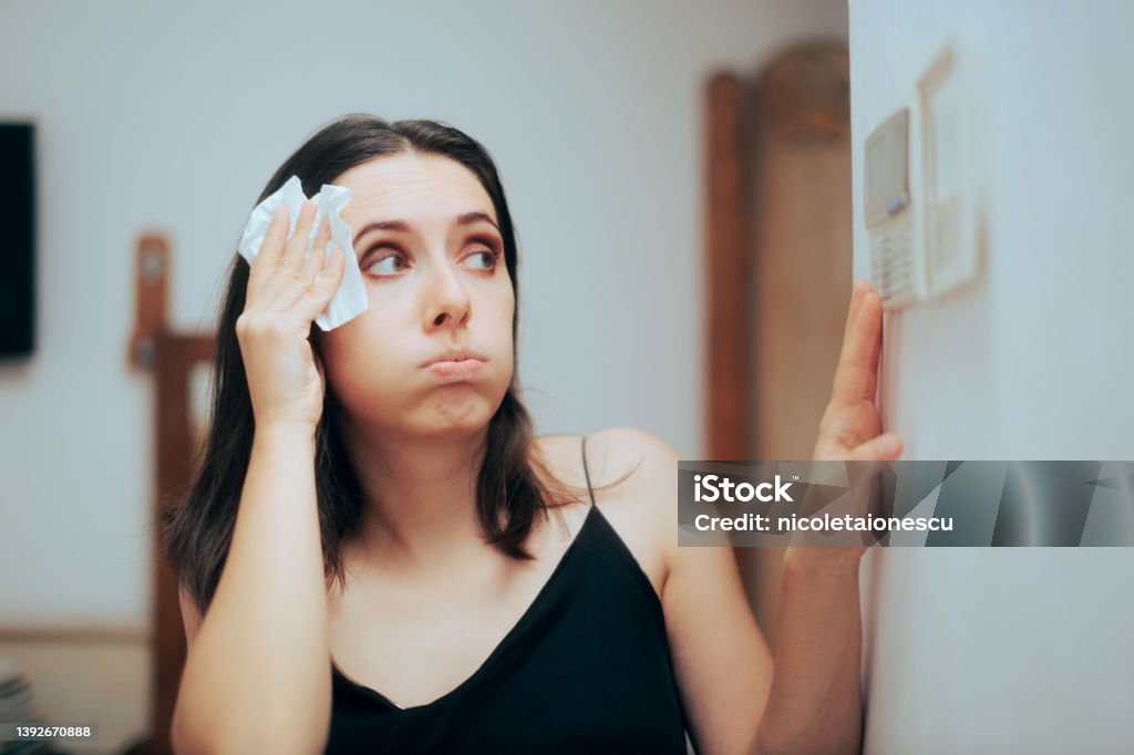 Woman Felling Hot During Summer Setting Her Thermostat Person adjusting temperature from the AC settings Air Conditioner Stock Photo