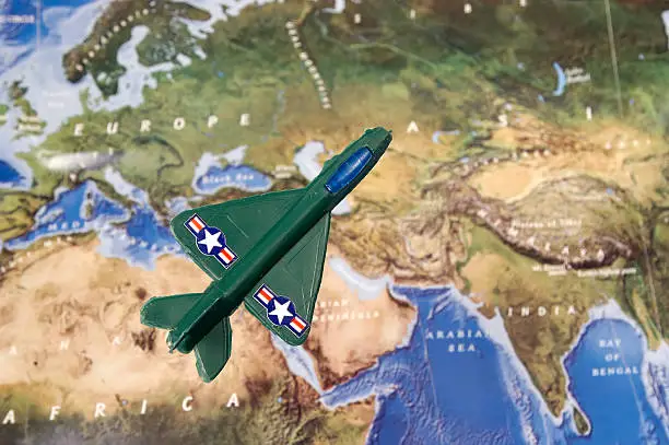 Photo of a Genric Toy Fighter Jet Elevated Above a Aerial Map.