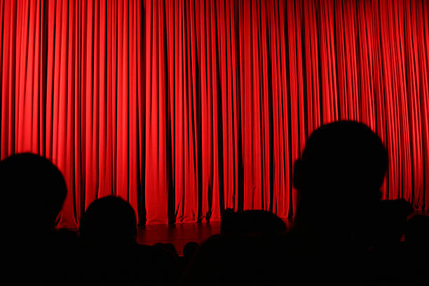 Audience silhouette and curtain An audience facing the stage during an intermission with the curtains drawn. curtain call stock pictures, royalty-free photos & images