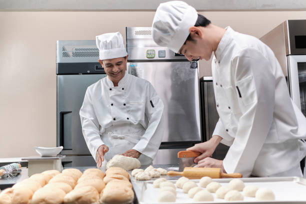 istock Asian male chefs in uniforms are preparing to bake bread in a stainless kitchen. 1392672113