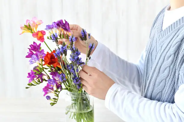 Woman's hands arranging flowers in living room