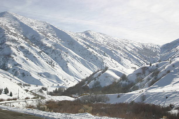 Snowy mountain landscape Mountains with snow on them in a cayon and a road leading up into the canyon. tooele stock pictures, royalty-free photos & images