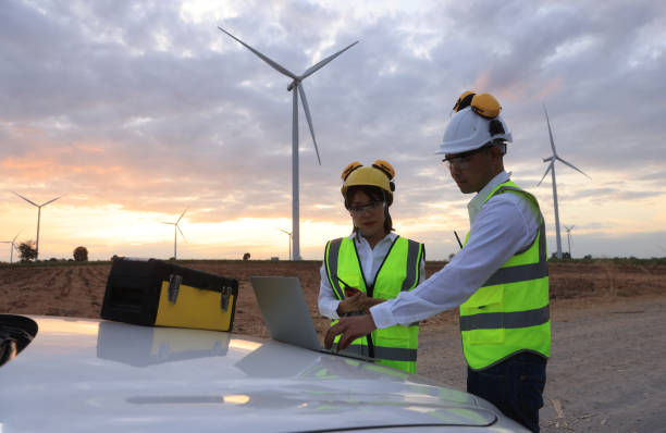 istock Young engineer discussion about wind turbine project at wind turbine farm. Two engineers discussed the plan for the maintenance of wind turbines 1392676784