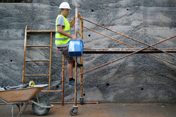 Worker climbing scaffolding with bucket in hand.