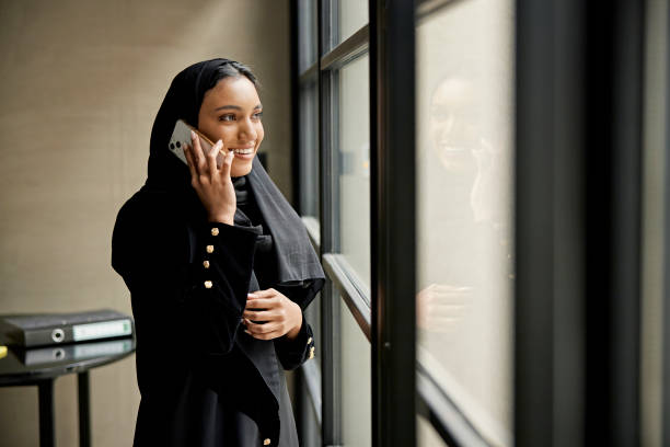 Smiling young Saudi businesswoman using phone stock photo