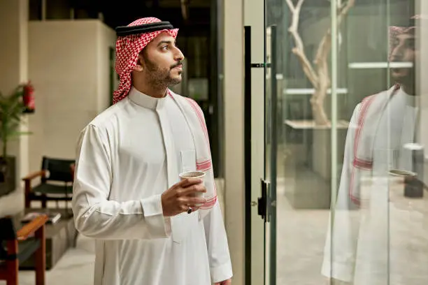 Photo of Indoor portrait of late 20s Riyadh businessman with coffee