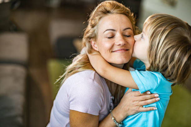 istock Affectionate boy kissing his single mother at home. 1392684150