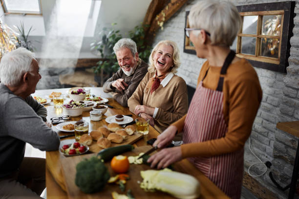 istock Cheerful senior couples talking during social gathering in dining room. 1392686516