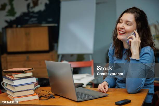 Beautiful Postgrad Using Laptop And Phone At The Desk In The University Office Stock Photo - Download Image Now