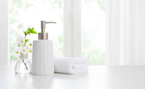 Soap dispenser with towels and aromatic flowers on light background stock photo