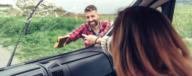 istock Man cleaning van windshield while woman pointing stain 1392696289