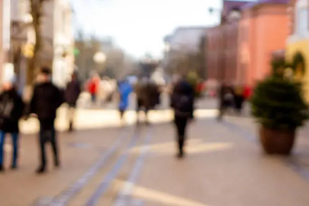 People walking in the street in soft focus. Blurred men and women outside on a sunny day. Abstract background. A backplate for web design. Concept of everyday life