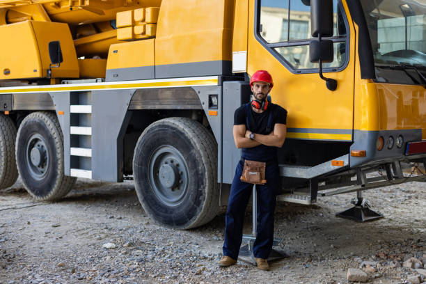 Young Building Worker is Standing at a Construction Site in Front of Construction Machinery and Feeling Successful and Confident.