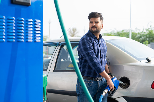 young man fueling car at petrol or gas filling station - concept of transportation, transportation and self-service