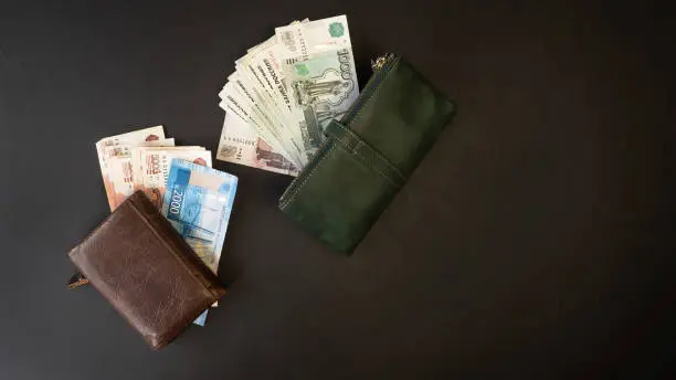 Russian money. Close-up of a green and brown wallet full of banknotes 5000, 2000, 1000, 500 rubles. Black background. Men's and women's wallet.