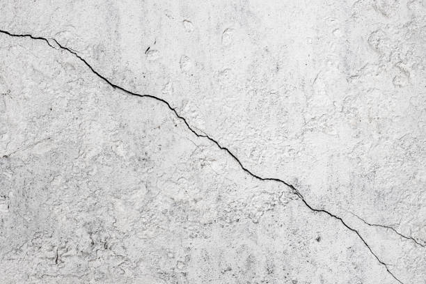 istock Cracked concrete wall surface with white paint for background 1392699975