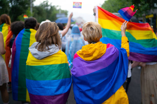 Supporting sexual issues and human rights Supporting sexual issues and human rights, two women attending pride event wearing pride and bisexual flags transgender protest stock pictures, royalty-free photos & images