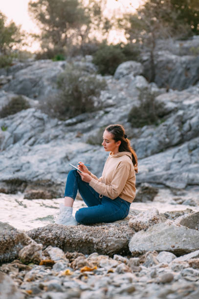istock Young Woman Drawing on a Sketchbook on the Beach 1392703829