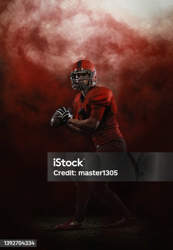 istock Red sky. Creative portrait of young man, american football player at stadium in motion on smoked background. Sport, challenge, goals, activity, sportlife concept. 1392704334