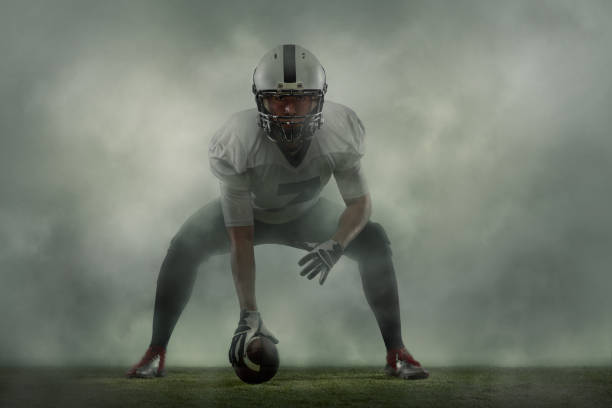 One portrait of young man, american football player at stadium in motion on smoked background. Sport, challenge, goals, activity, sportlife concept. Linebacker. Creative portrait of young man, american football player at stadium in motion on smoked background. Sport, challenge, goals, activity, sportlife concept. Poster, flyer for ad, design. Touchdown stock pictures, royalty-free photos & images