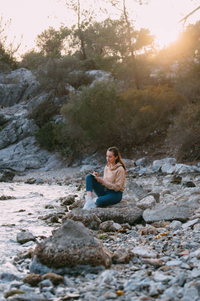 istock Young Woman Drawing on a Sketchbook on the Beach 1392706124
