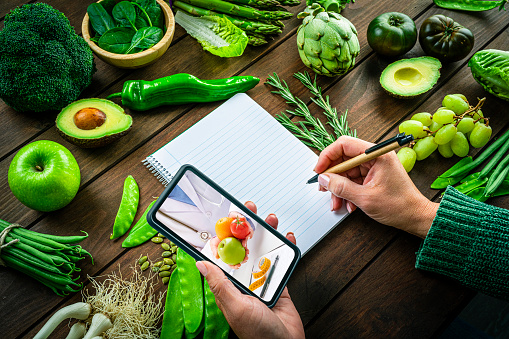 Woman holding smartphone talking with nutritionist about the benefits of eating fresh fruits and vegetables.