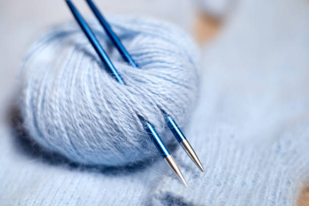 istock Blue knitted women's sweater with patterns, balls of thread and knitting needles 1392707083