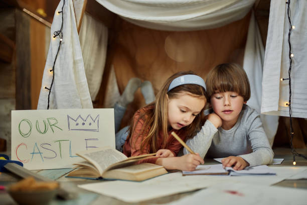 Small brother and sister doing their homework while relaxing at their room.