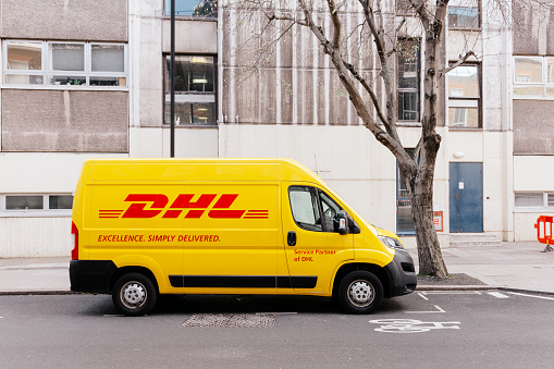 London, UK - 20 April, 2022: a yellow DHL delivery van parked on a city street in central London, UK.