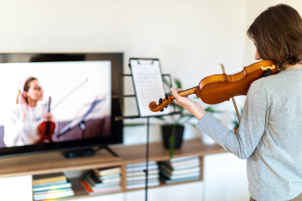 istock Boy learning to play violin with teacher online 1392708476