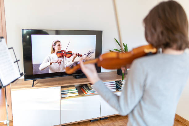 istock Boy learning to play violin with teacher online 1392708490