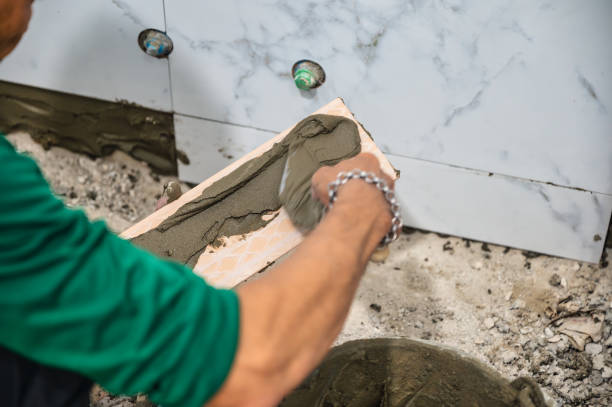istock Male tiler using trowel laying marble tile with cement in bathroom. Housing development, improvement renovation 1392708509