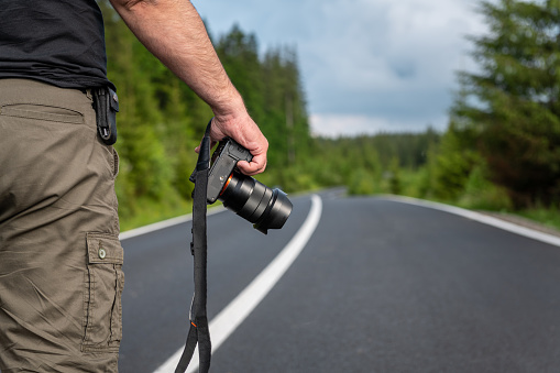 Photographer with camera on the road in mountains, travel photography