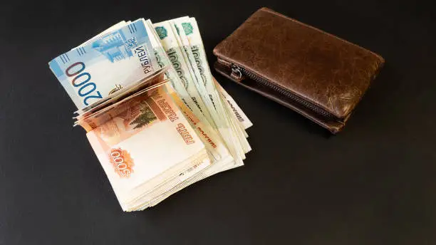 Russian money. Close-up of a brown wallet full of banknotes 5000, 2000, 1000, 500 rubles. Black background. Money in your wallet.