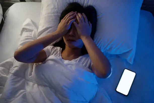 Asian woman stressed on social media in bed