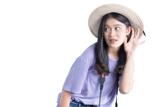 Asian woman with hat and camera hearing something isolated over white background
