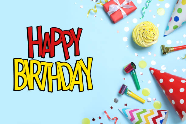 istock Happy Birthday! Flat lay composition with party hats, decor and cupcake on light blue background 1392712970