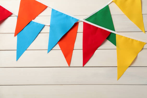 istock Buntings with colorful triangular flags hanging on white wooden wall. Festive decor 1392713899