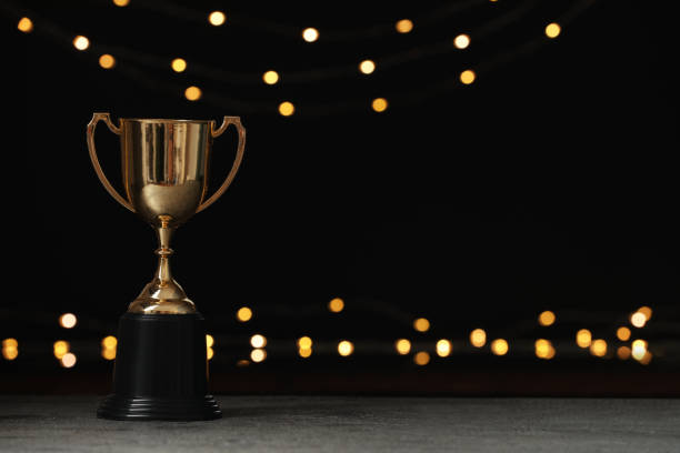 istock Golden trophy cup on table against blurred festive lights, space for text 1392713919
