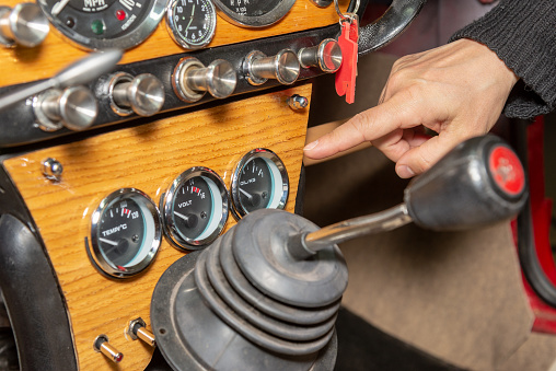old car control panel with a hand pointing at the control clocks and the gear lever on a wooden panel