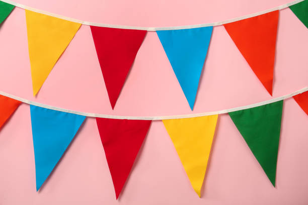 istock Buntings with colorful triangular flags on pink background. Festive decor 1392714148