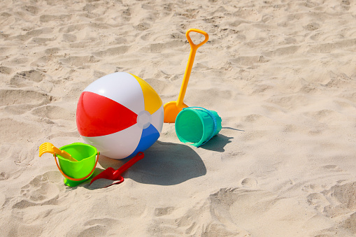 Different beach toys and inflatable ball on sand outdoors, space for text