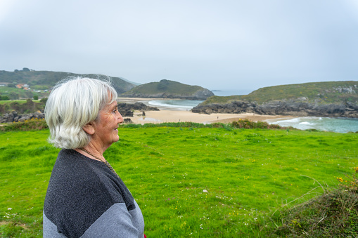 An elderly woman on a trail at Barro beach on the Borizu peninsula in the town of Llanes. Asturias. Spain