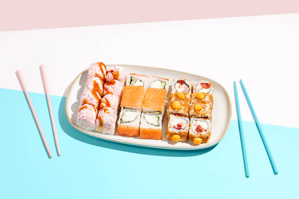 istock Set maki rolls on coloured background. Sushi roll assortment on ceramic plate. Maki sushi in minimal style. Japanese menu concept. 1392717182