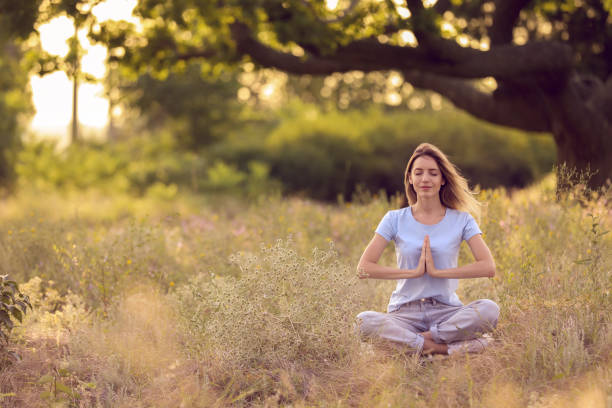 istock Young woman meditating on green grass in park, space for text 1392717294