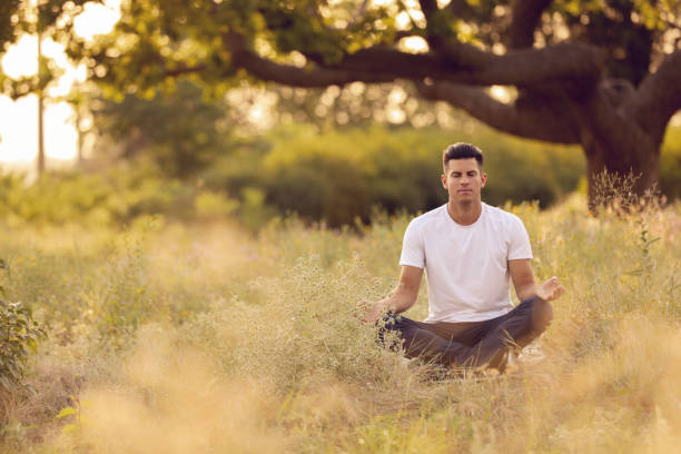 istock Man meditating on green grass in park, space for text 1392718543