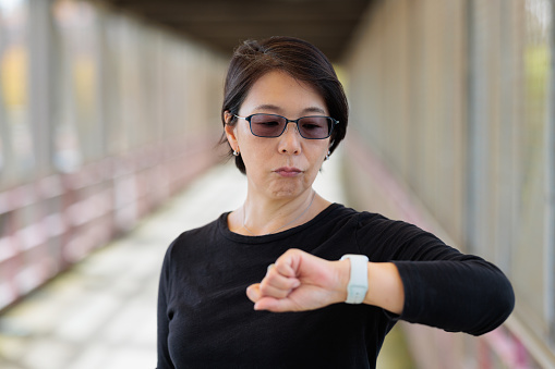 Woman with an unhappy expression looking at her watch.