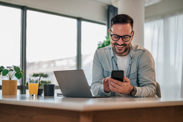 istock Distracted smiling businessman using smart phone while working at desk in office 1392720318
