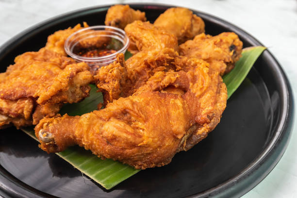 istock Appetizing fried chicken that sits on a banana leaf in a black plate. 1392721133