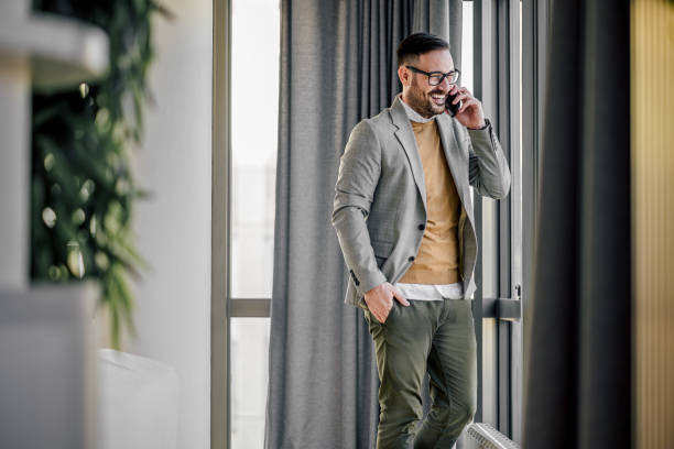 istock Happy entrepreneur talking on smart phone while looking through window at office 1392721317